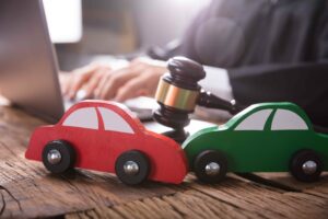 Fender bender crash: red and green toy cars crash on a desk with a gavel