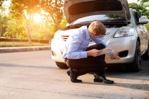 Fender bender accident: inspector with clip board looking at the front of a car after an accident