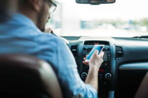 How many accidents are caused by distracted driving: man looking at smartphone while driving